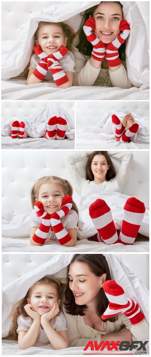 Cheerful little daughter and mom on bed stock photo