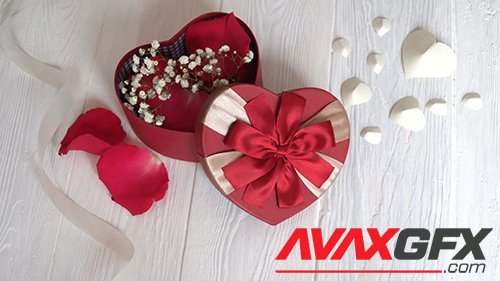 Footage - Gift box in form of heart and red ribbon on wooden white background. Top view
